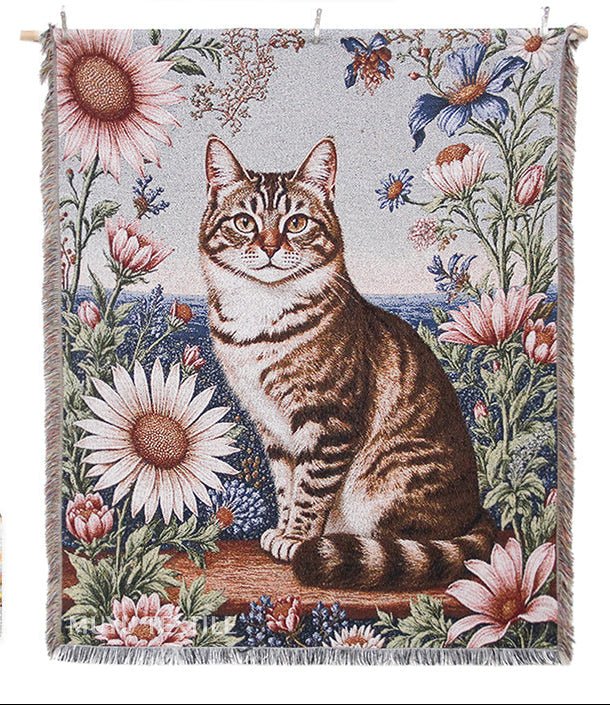 Woven blanket with a cat and floral design, featuring brand logos on a white background.
